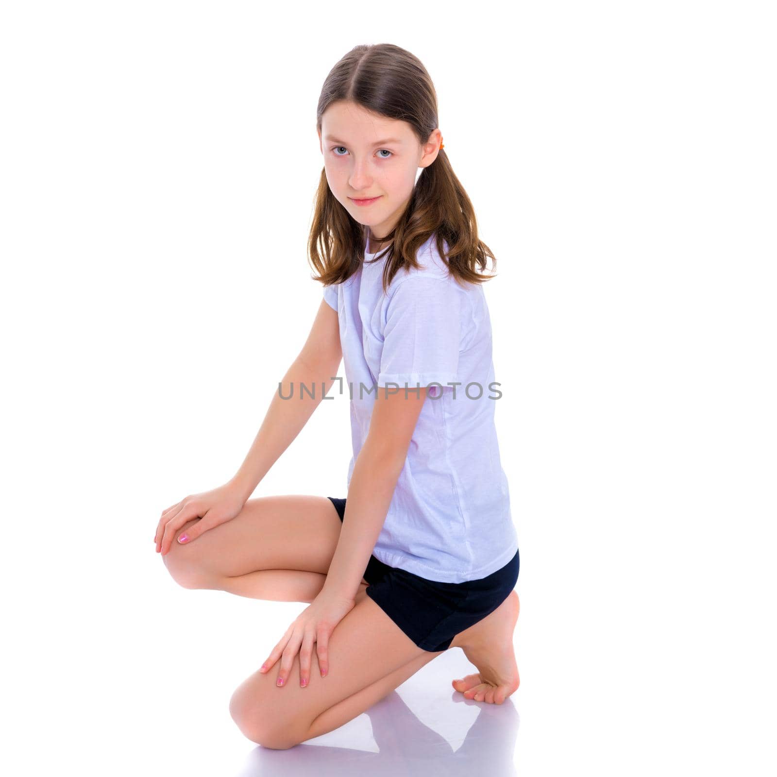 Beautiful little girl kneels in the studio on a white background. The concept of beauty and fashion, children's emotions. Isolated.