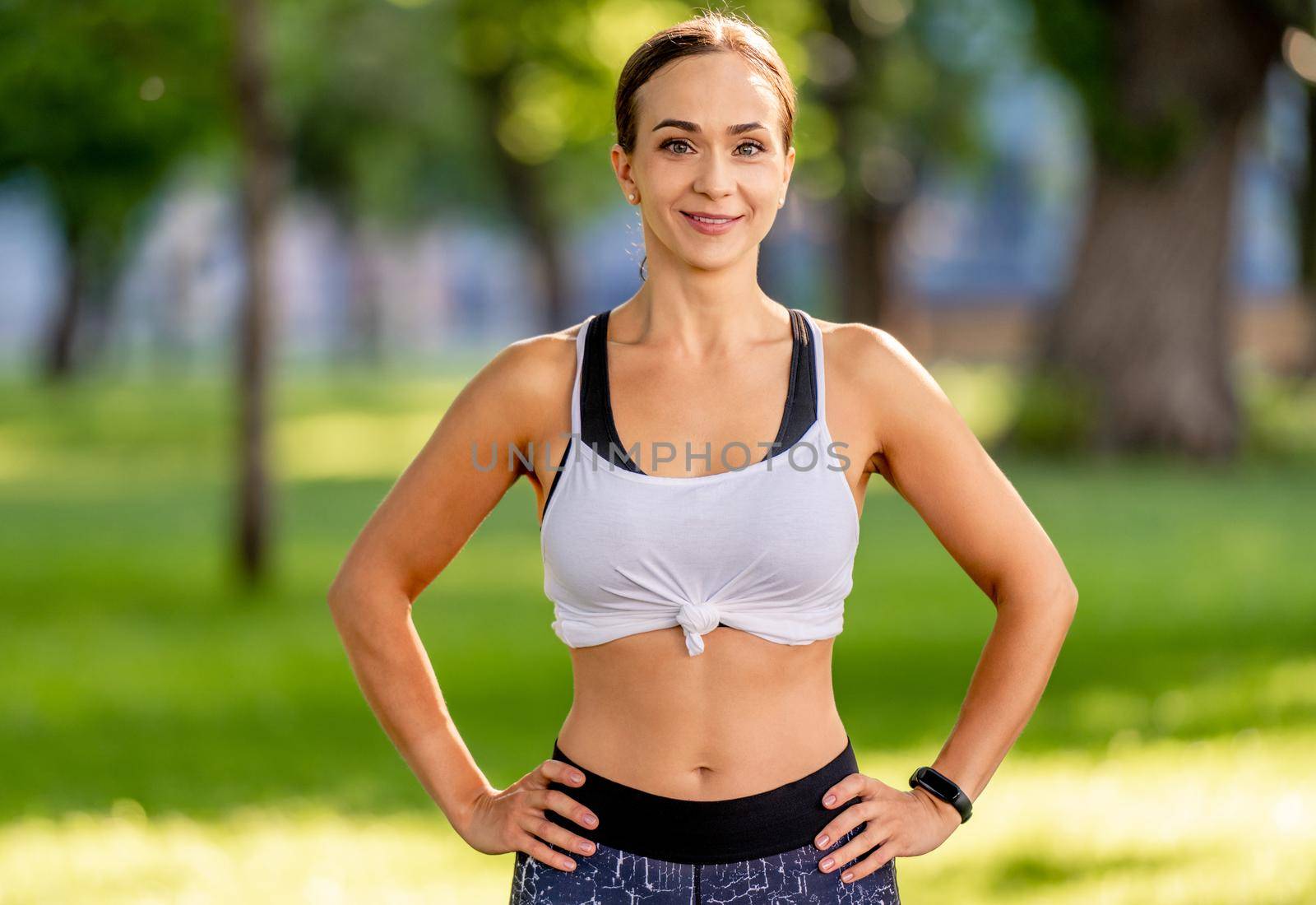 Beautiful yoga girl portrait at nature in summertime. Young sport woman looking at camera and smiling after workout