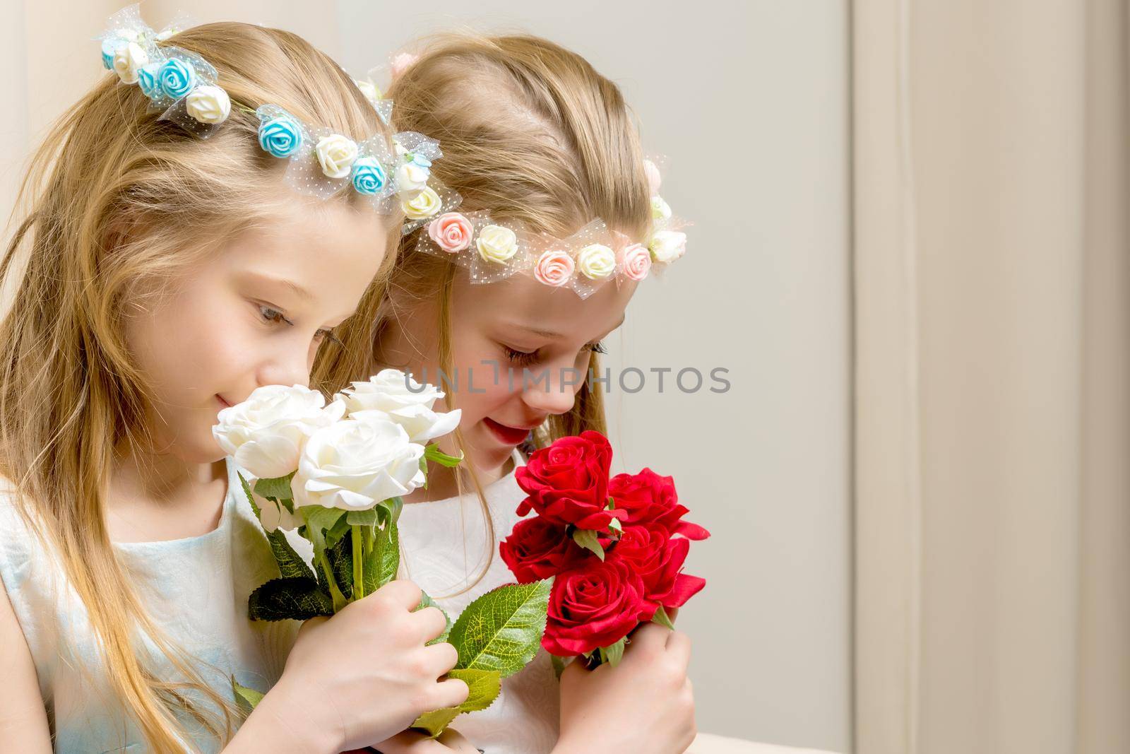 Two beautiful little girls with flowers in the studio. The concept of happy people, children.