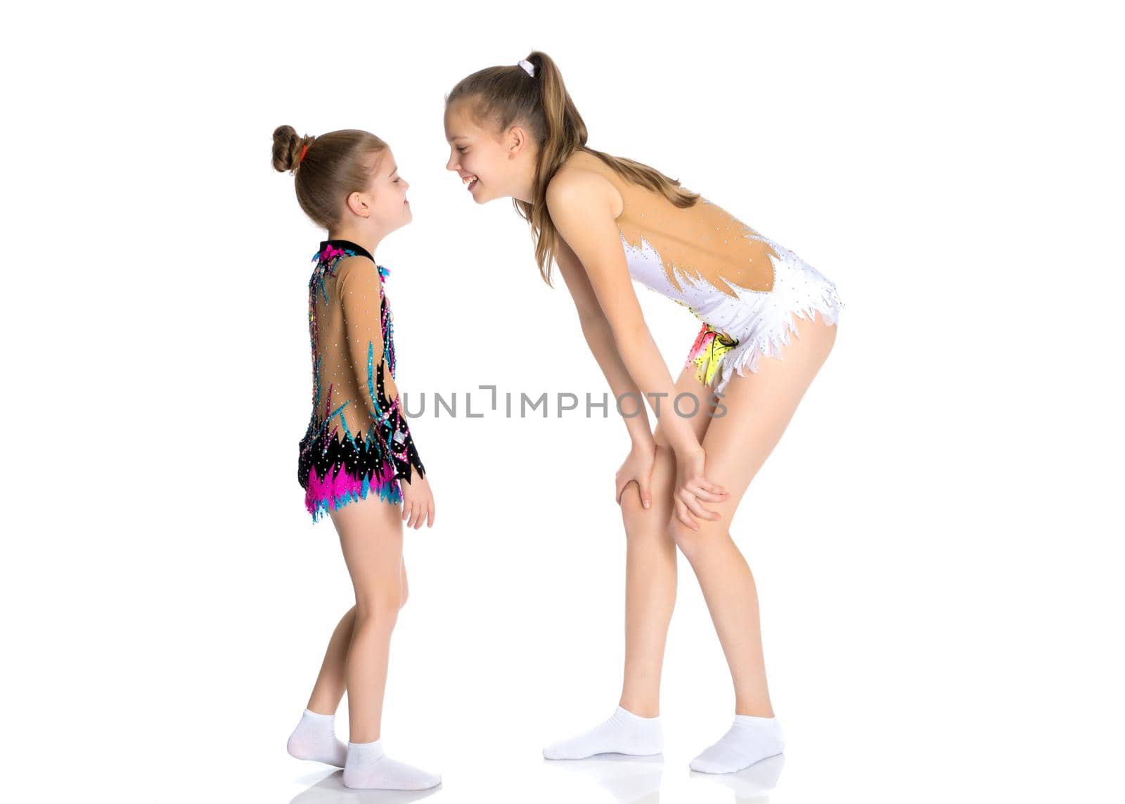 Lovely little girls gymnasts warm up before the competition. The concept of a happy childhood, sports and fitness. Isolated on white background.