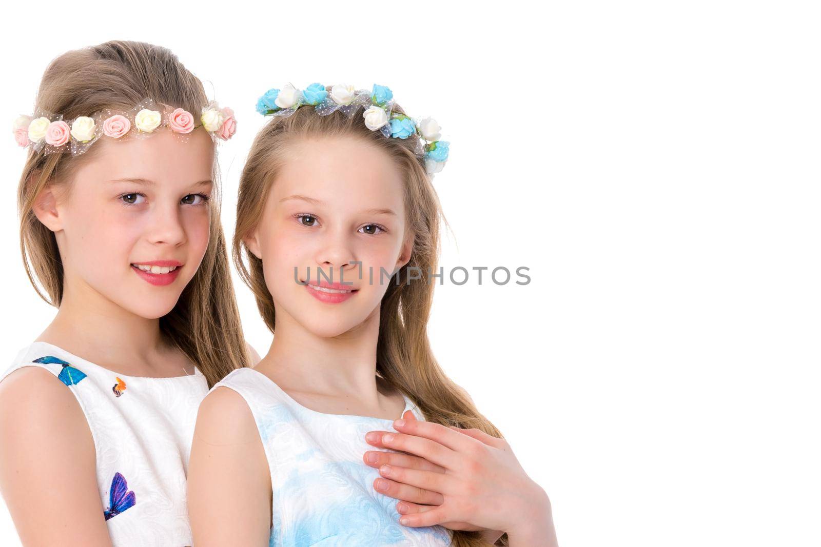 Two cute little girls close-up, in the studio on a white background. The concept of a happy childhood, Beauty and fashion. Isolated.