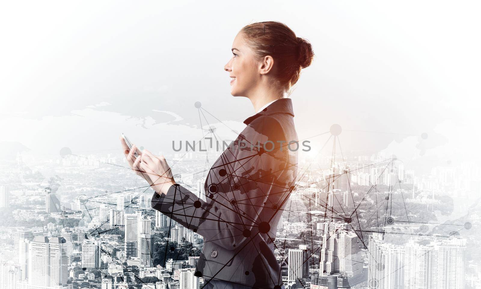 Young businesswoman using mobile phone. Double exposure concept with modern downtown architecture and beautiful woman in business suit. Digital technology in property management and development.