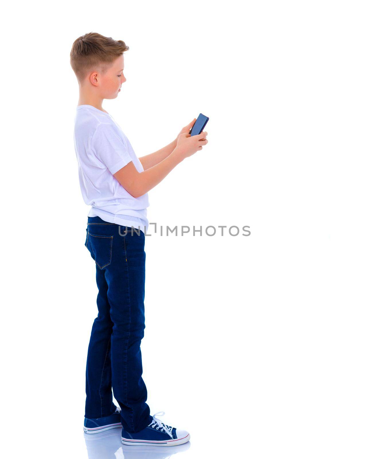 A small boy of school age uses a mobile phone. The concept of digital technology, communication between people. Isolated on white background.