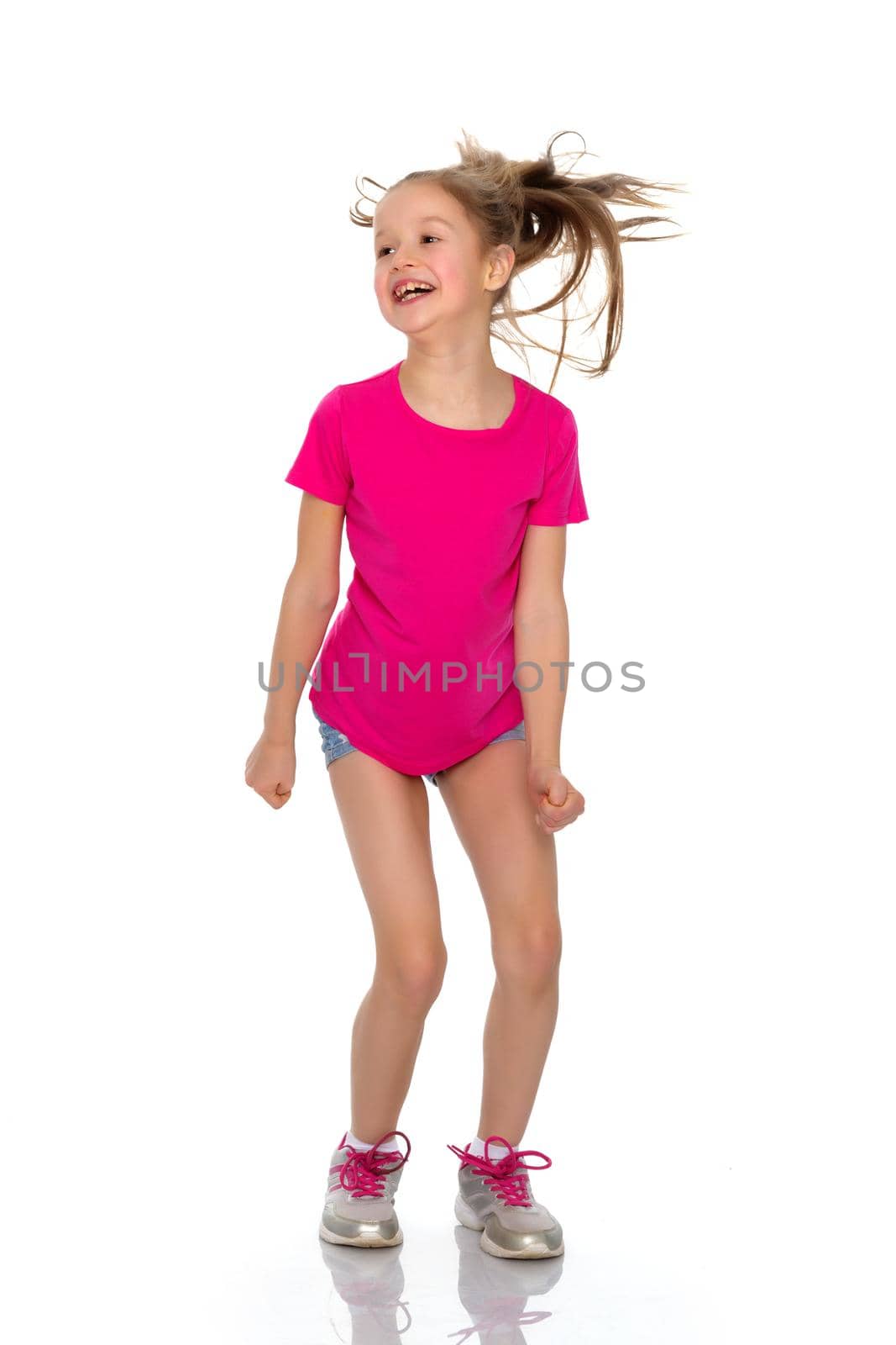 A little girl gymnast joyfully jumps and wags her hands. The concept of sport and fitness. Isolated over white background