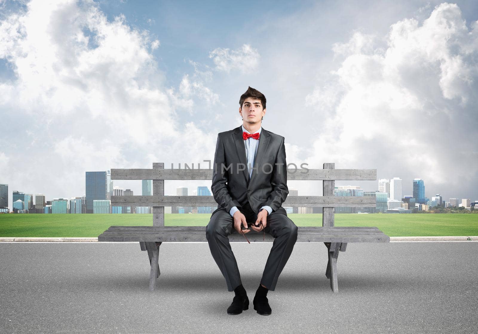 Young businessman sits on a bench and holds glasses