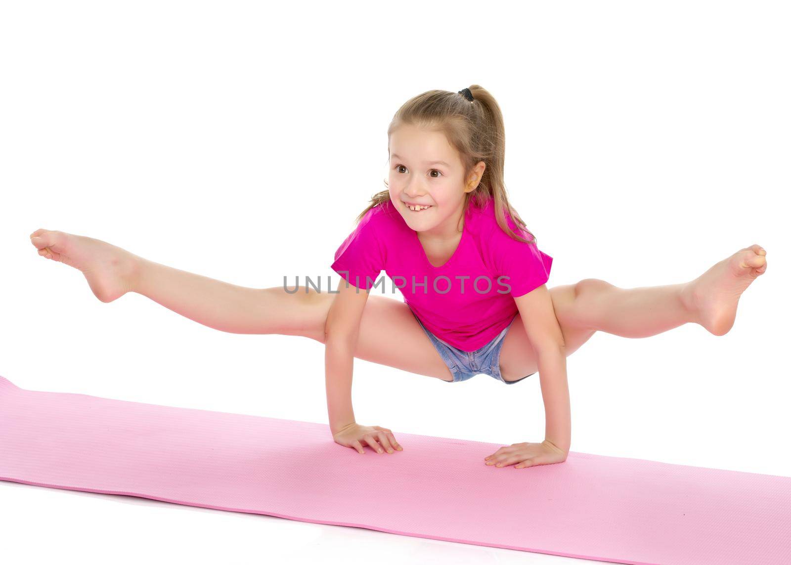 A girl gymnast performs an acrobatic element on the floor. The concept of childhood, sport, healthy lifestyle. Isolated on white background.