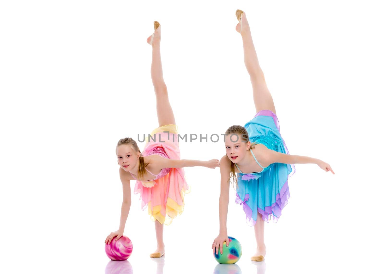 Two cheerful little girls gymnasts in competitions, perform exercises with the ball. The concept of children's sports, fitness, healthy lifestyle. Isolated on white background.