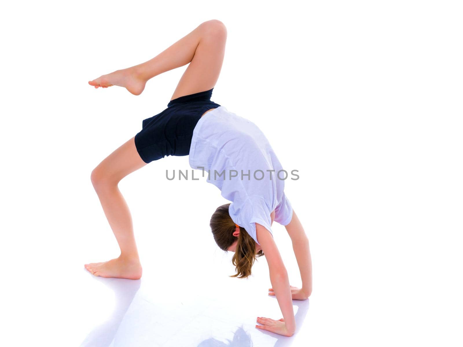 A girl gymnast performs an acrobatic element on the floor. The concept of childhood, sport, healthy lifestyle. Isolated on white background.