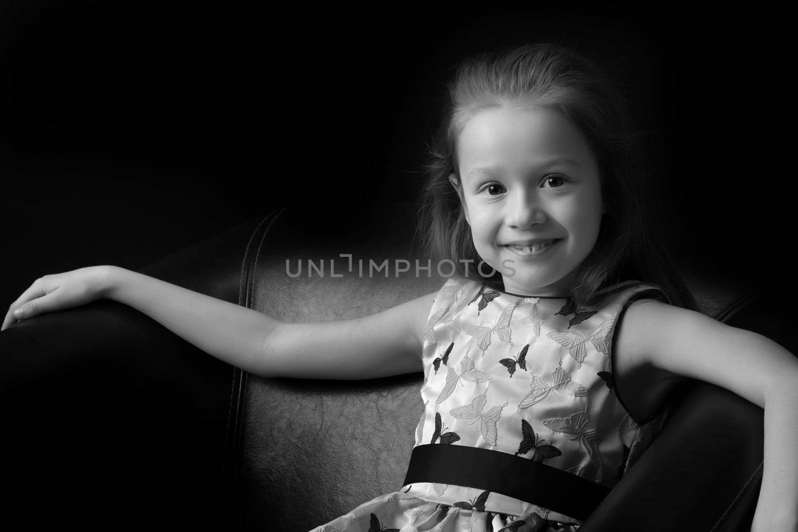 Beautiful little girl, studio portrait on a black background. The concept of a happy childhood, style and fashion.