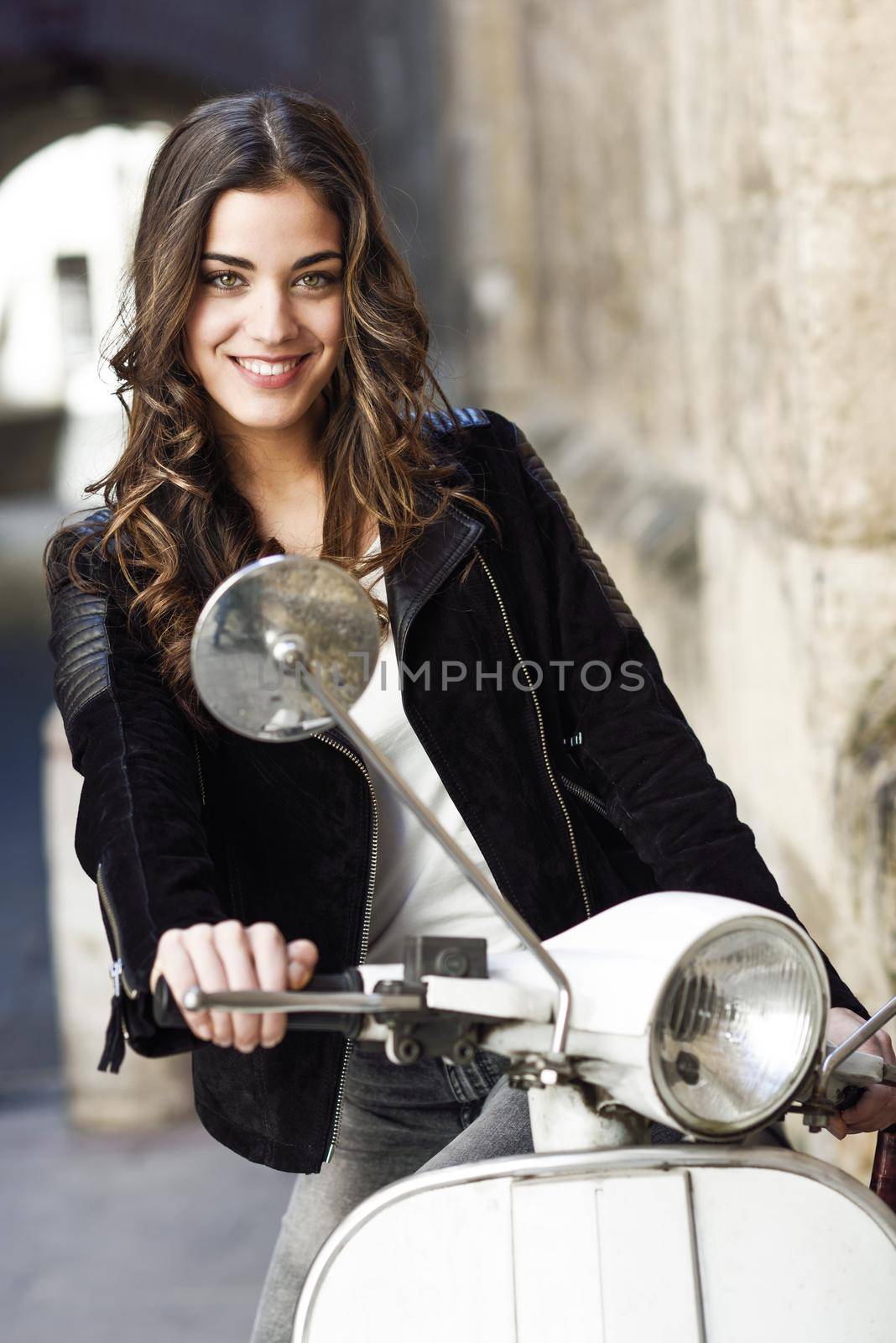 Woman in urban background smiling and wearing casual clothes with a old scooter in the background