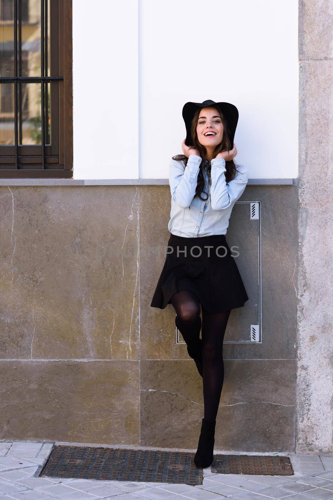 Portrait of young woman in urban background wearing casual clothes and hat