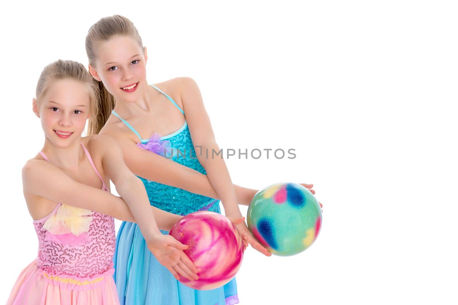 Two cheerful little girls gymnasts in competitions, perform exercises with the ball. The concept of children's sports, fitness, healthy lifestyle. Isolated on white background.