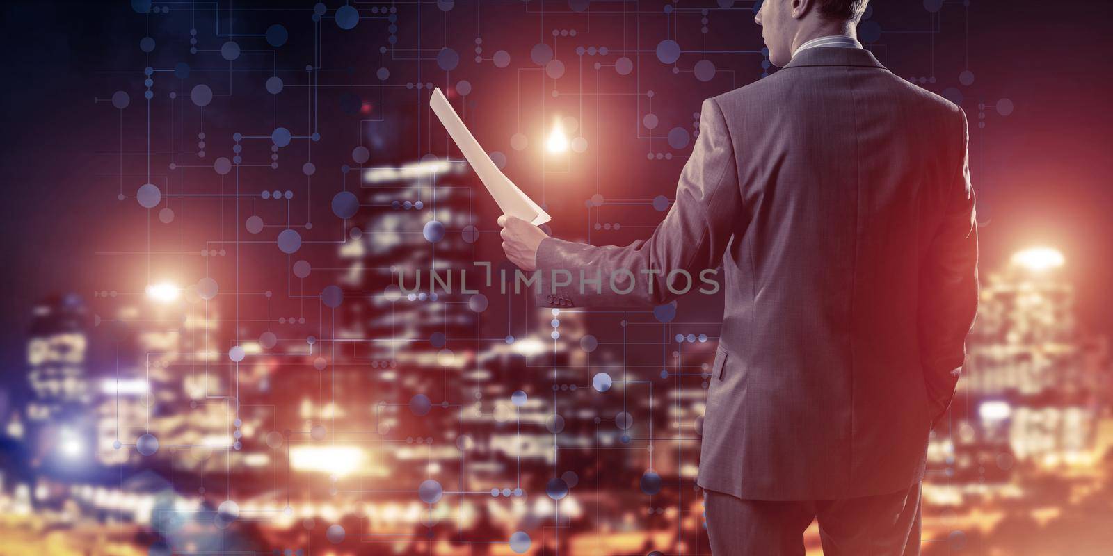 Rear view of businessman against night cityscape background and technology concept by adam121