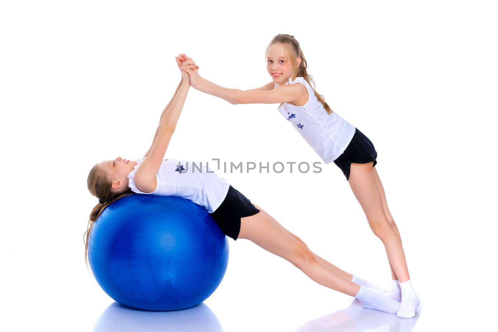 Girls gymnasts perform exercises with a large ball for fitness. by kolesnikov_studio