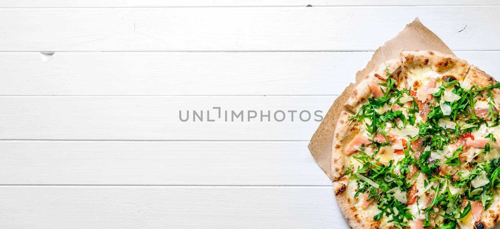 Itallian homemade pizza served on white wooden background with cutlery and cherry tomatoes. Copyspace, top view