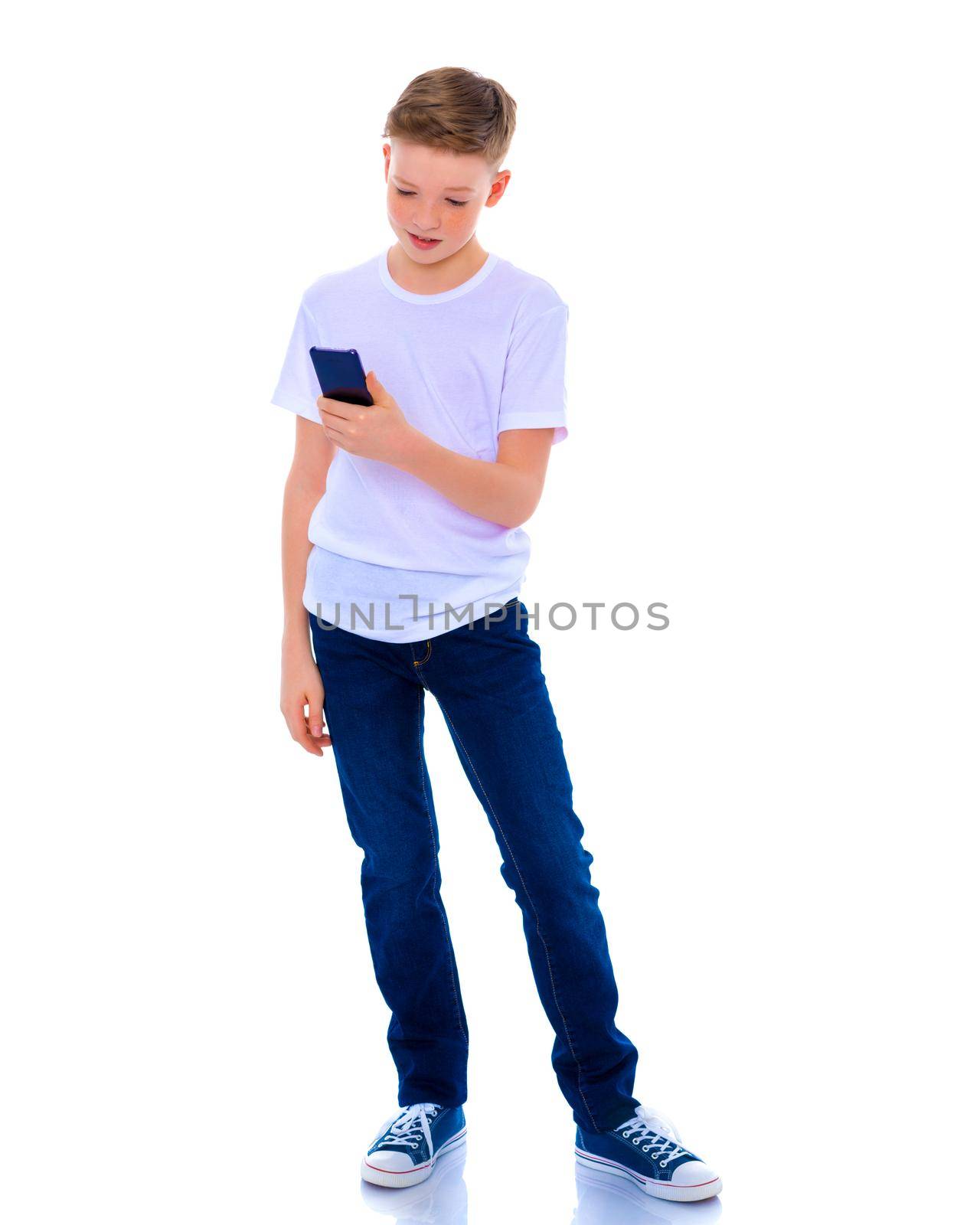 A small boy of school age uses a mobile phone. The concept of digital technology, communication between people. Isolated on white background.