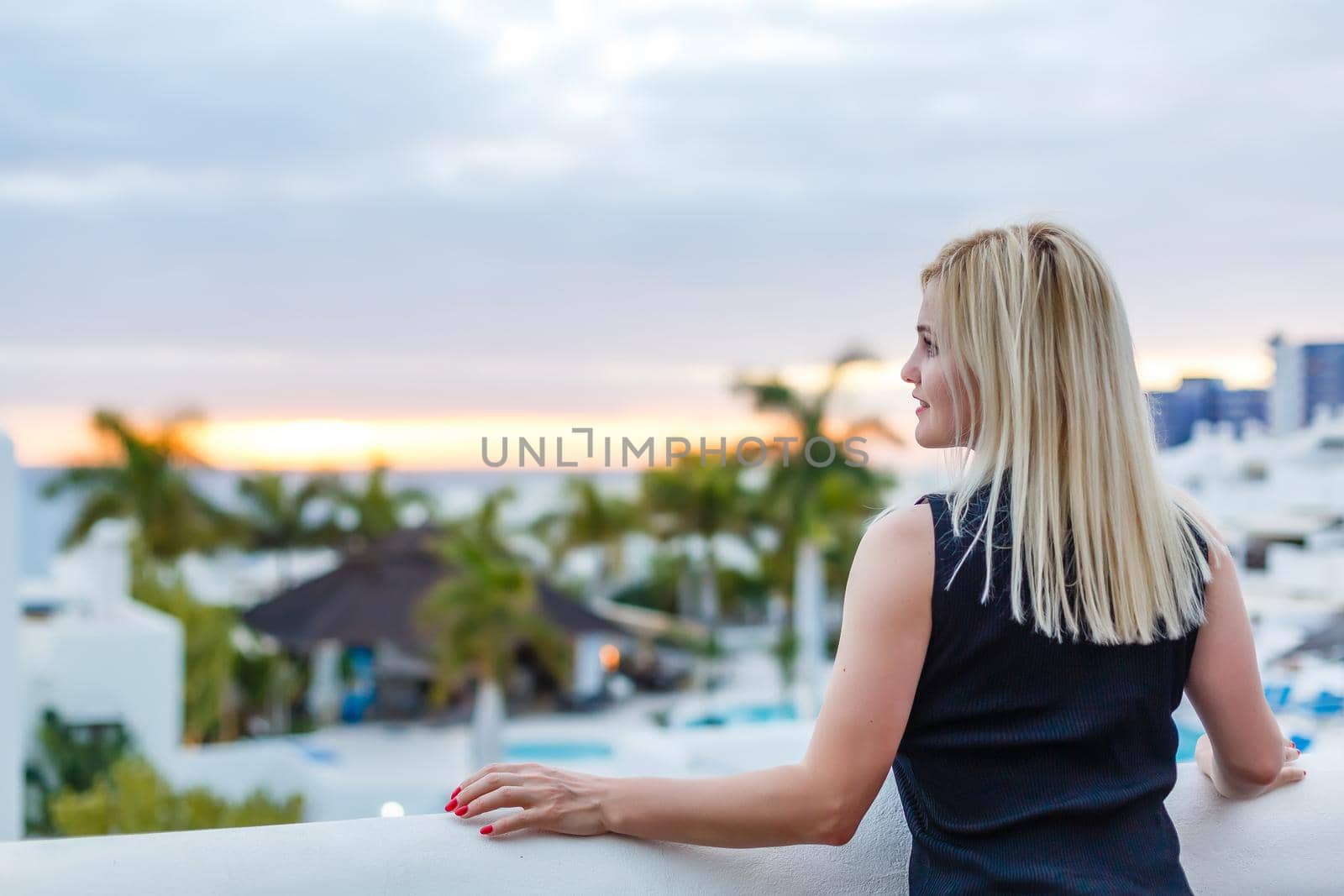 Young girl standing on the balcony overlooking the sea.