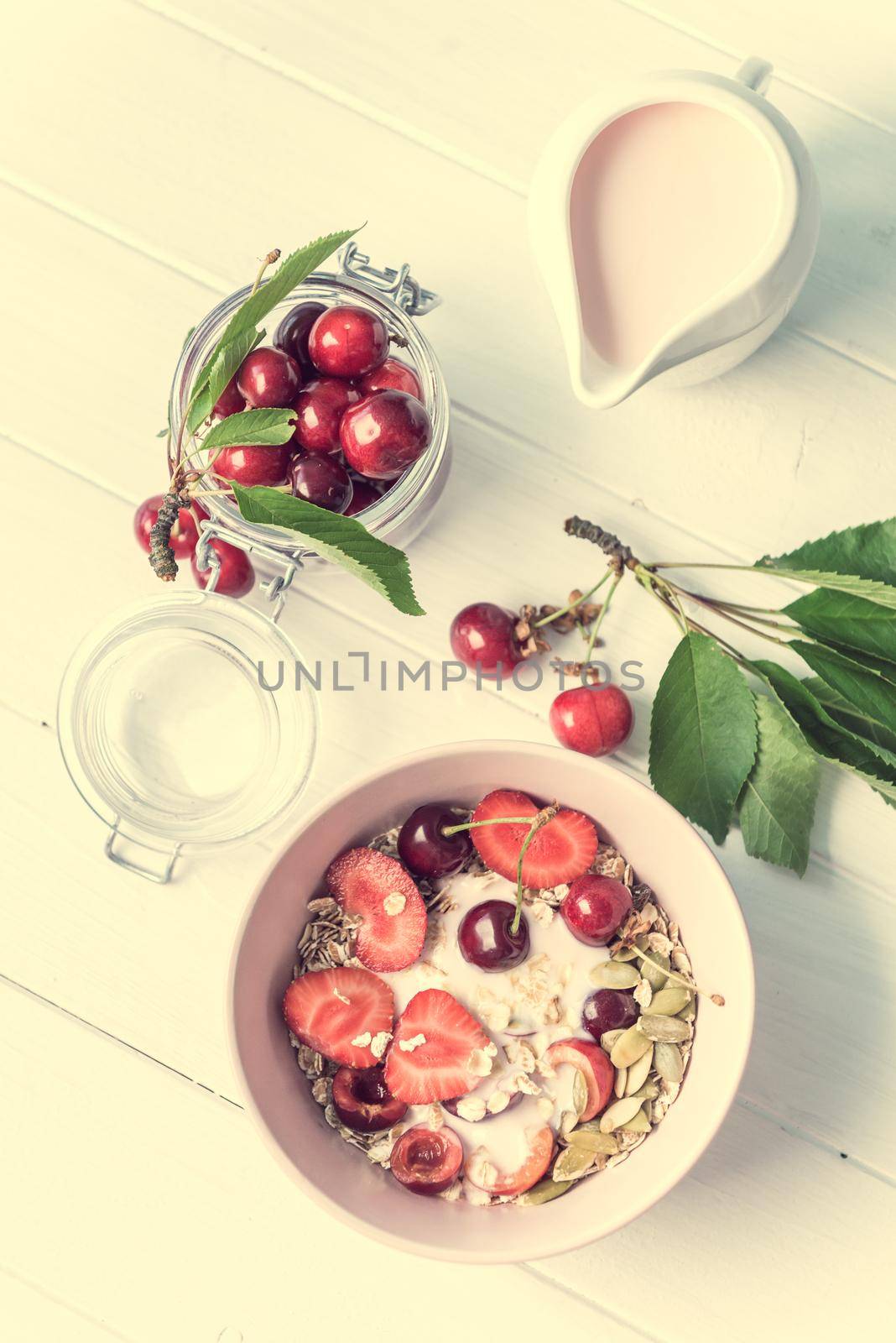 Healthy breakfast with muesli and cut cherries, rustic jar with yoghurt, topview