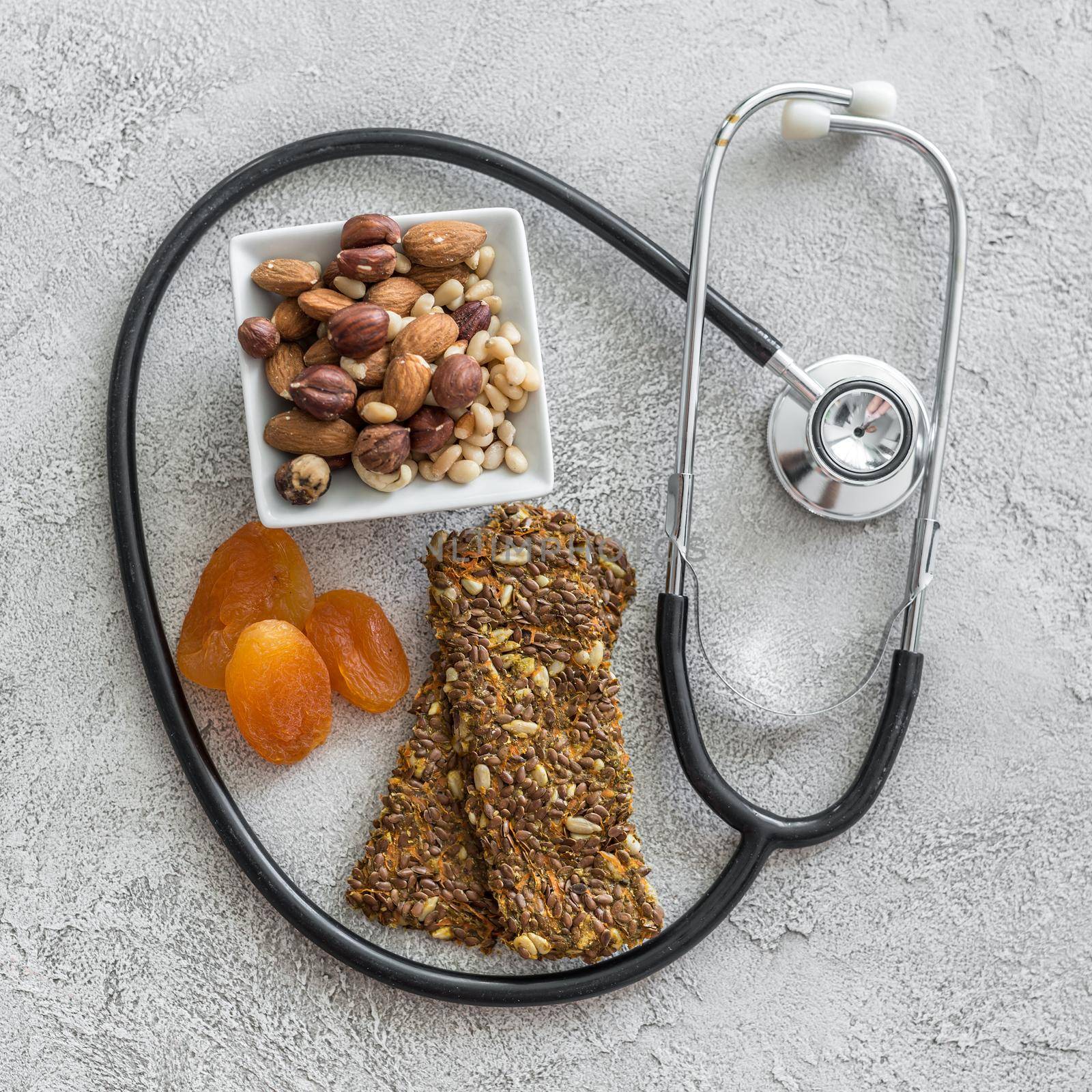 Stethoscope and heart with dried fruits and nuts on a gray background. Medicine concept