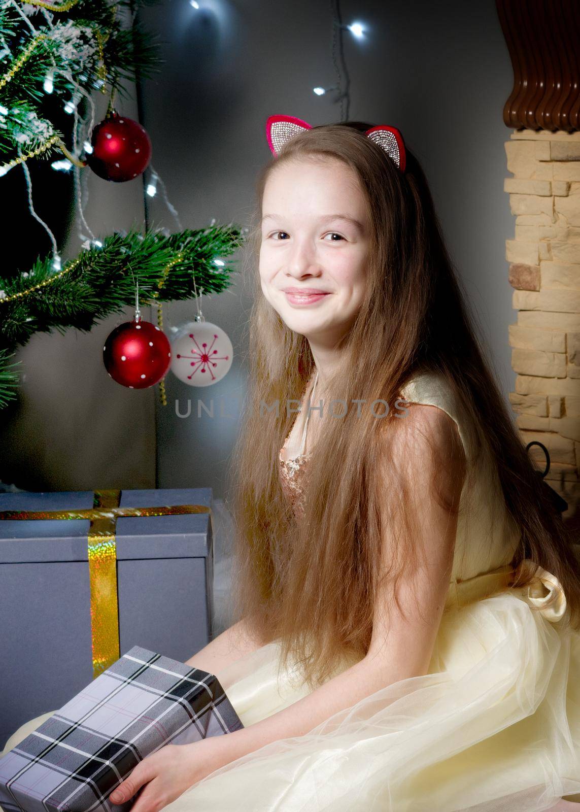 A teenage girl is sitting near the New Year tree. by kolesnikov_studio