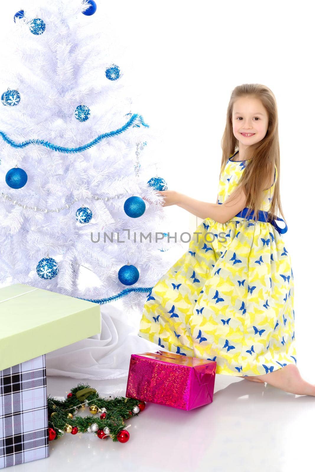 A happy little girl is decorating a Christmas tree. The concept of holidays, Christmas and New Year. Isolated on white background.