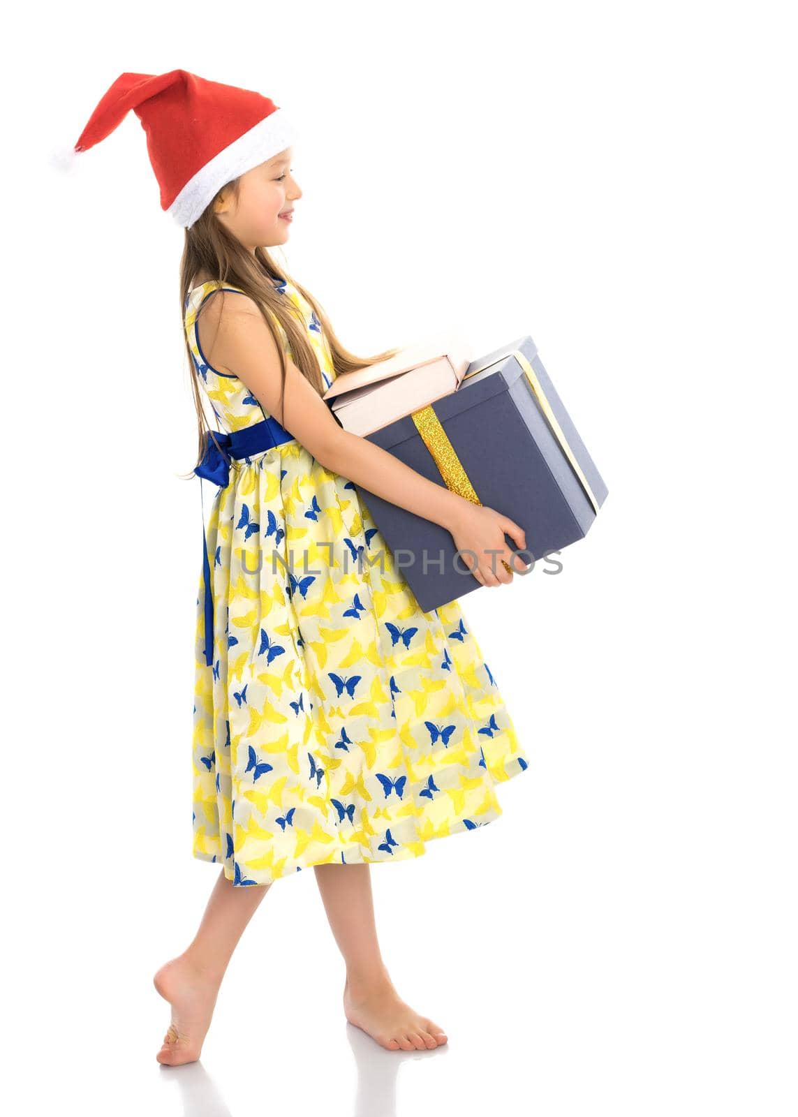 Beautiful little girl in a Santa Claus hat with a gift on a white background. The concept of Christmas, New Year's holidays. Isolated.