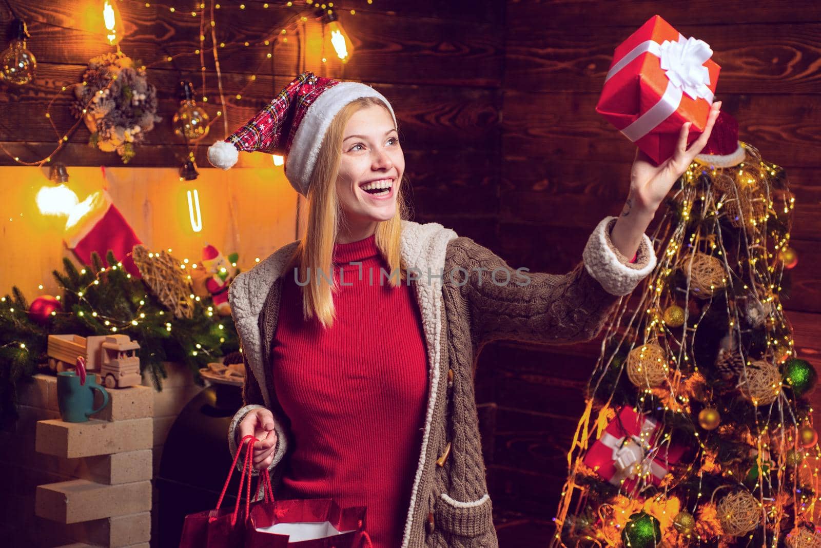 Young woman celebrates Christmas and holds present gift. Xmas tree. Happy new year. Concept of Merry Christmas and New Year. by Tverdokhlib