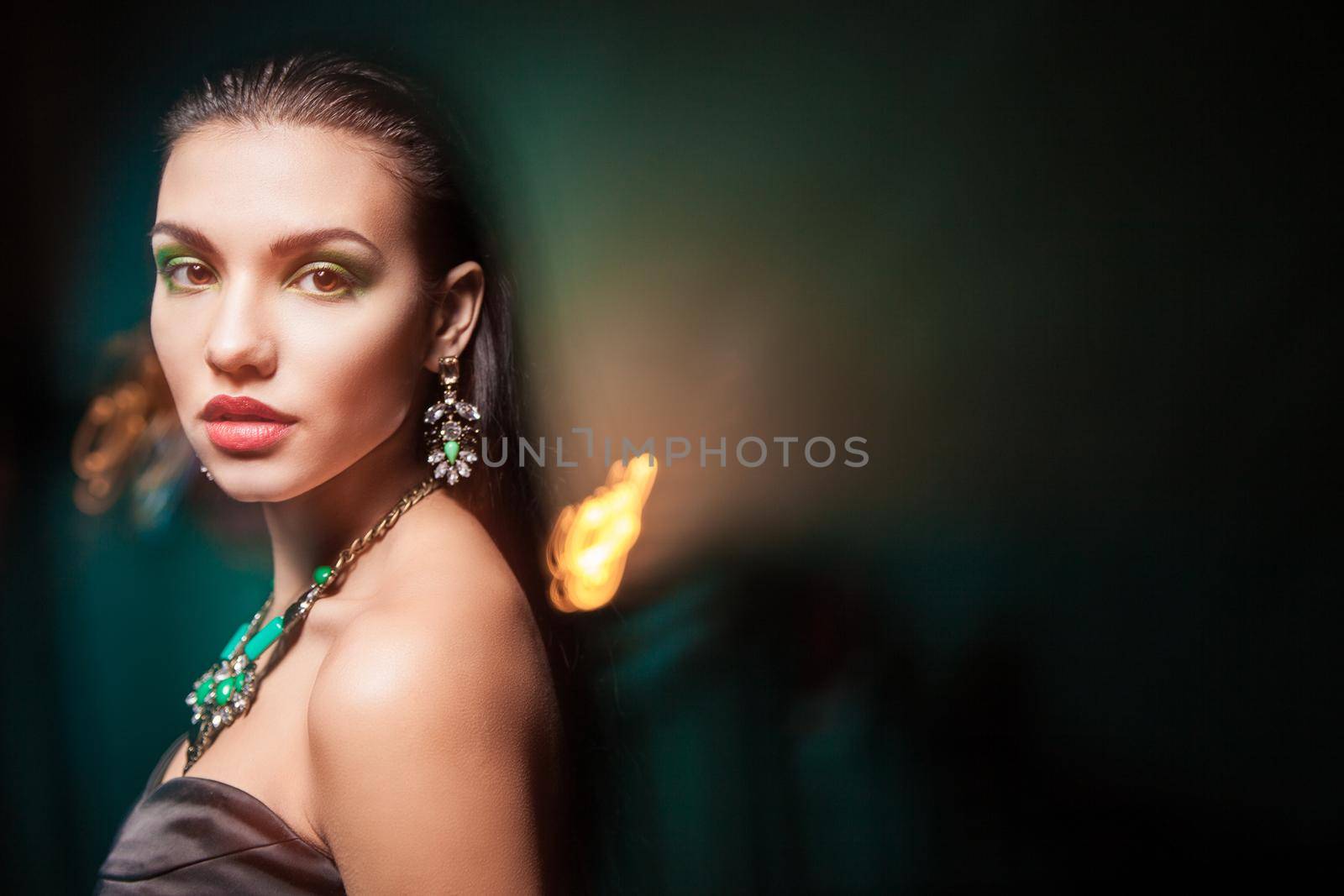 Beautiful woman with evening make-up over dark background. Jewelry and Beauty. Fashion photo
