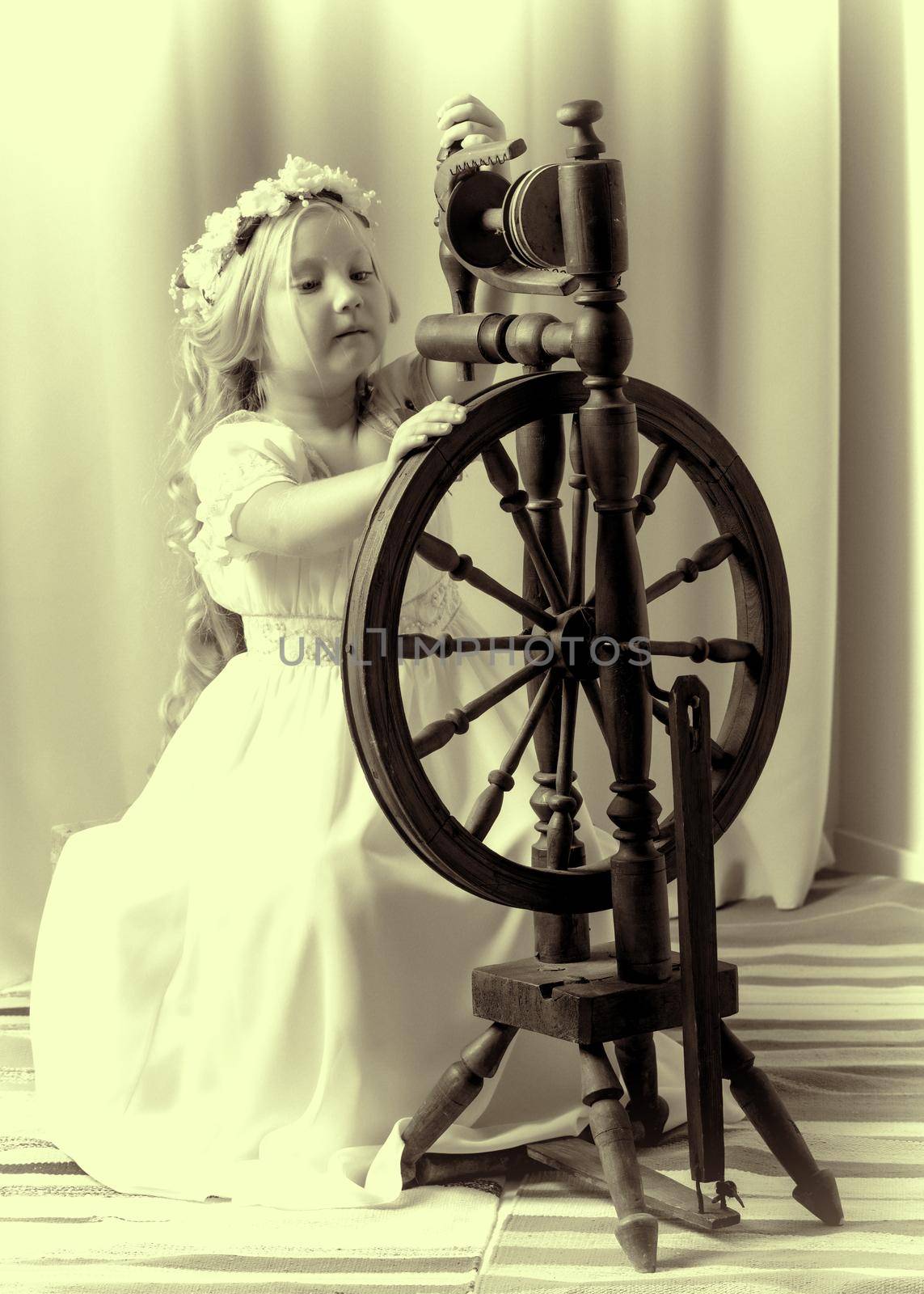 A cute little girl wove a wool with a rotating wheel. by kolesnikov_studio