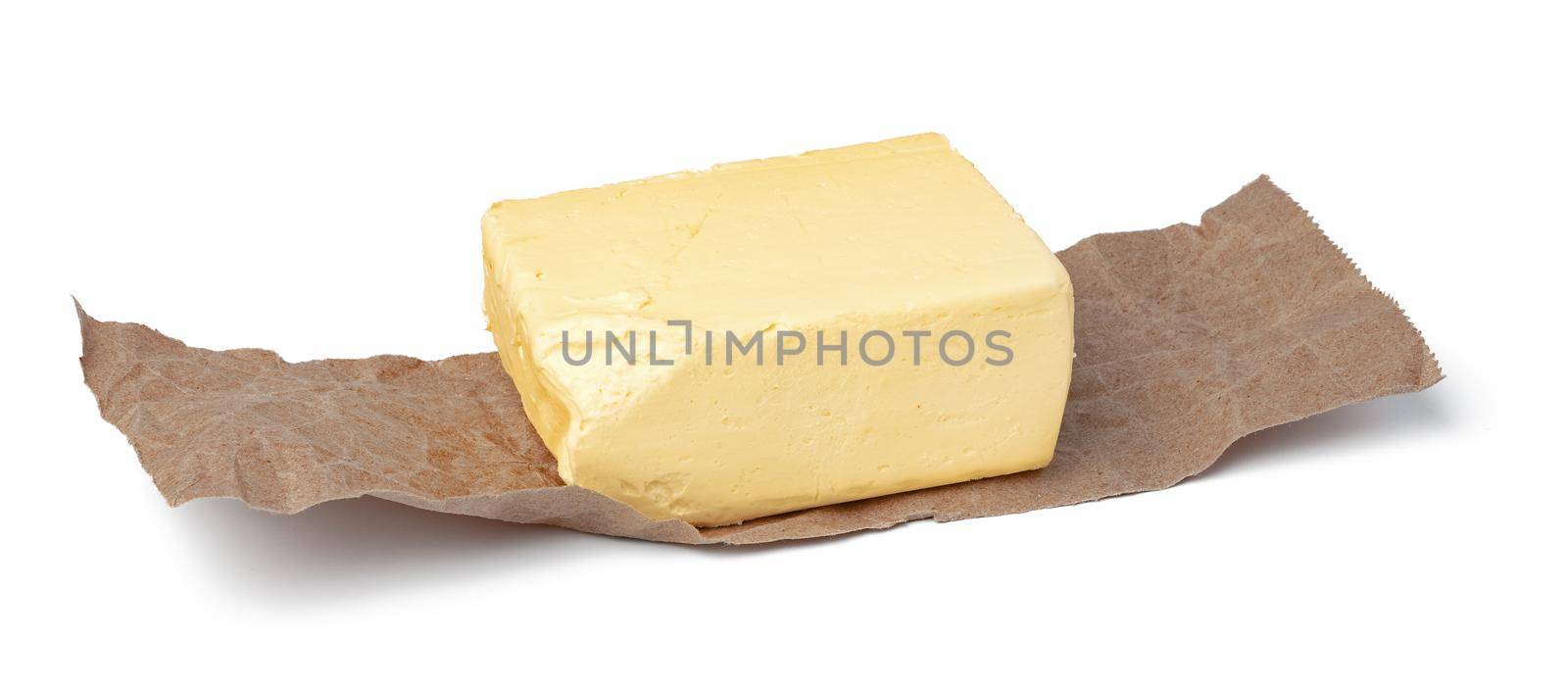 Fresh butter on craft paper isolated on white background. close up.
