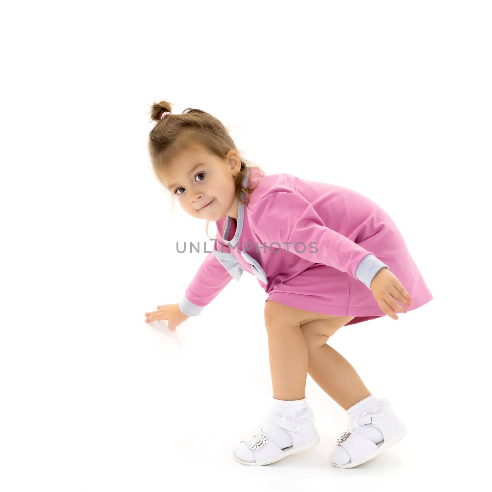 Beautiful little girl is sitting on the floor in the studio. The concept of a happy childhood, beauty and fashion. Isolated on white background.