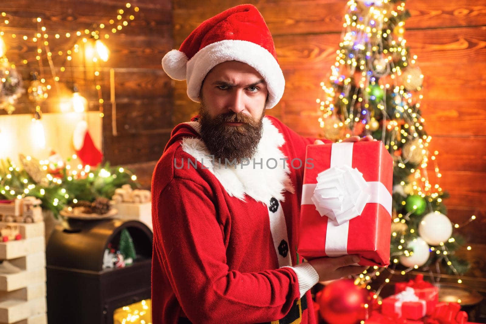 Delivery gifts. Gift emotions. Santa man holding gift. Hipster in red Santa hat holding present. Bearded santa