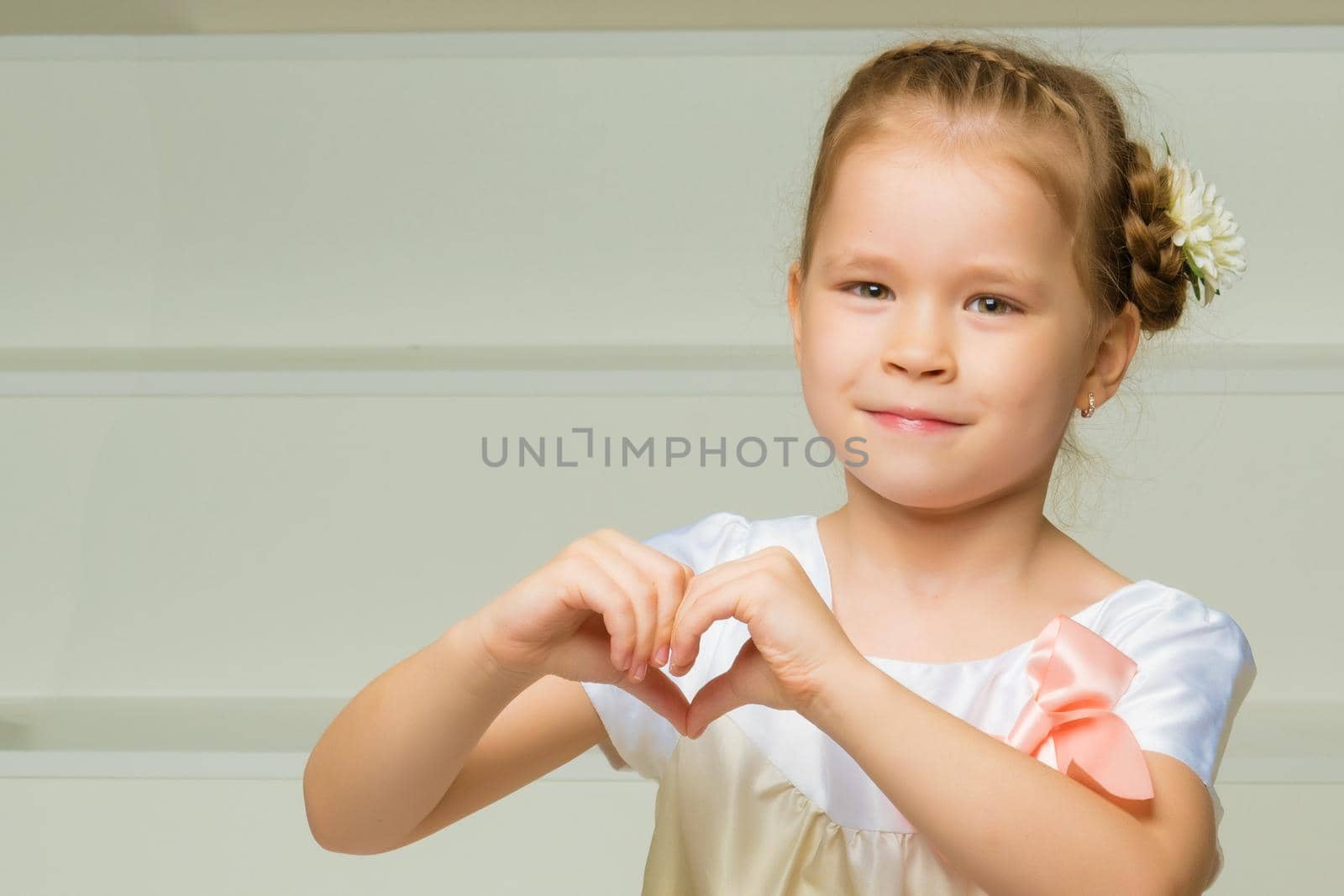 Beautiful little girl shows heart by hands. The concept of happy people, childhood.