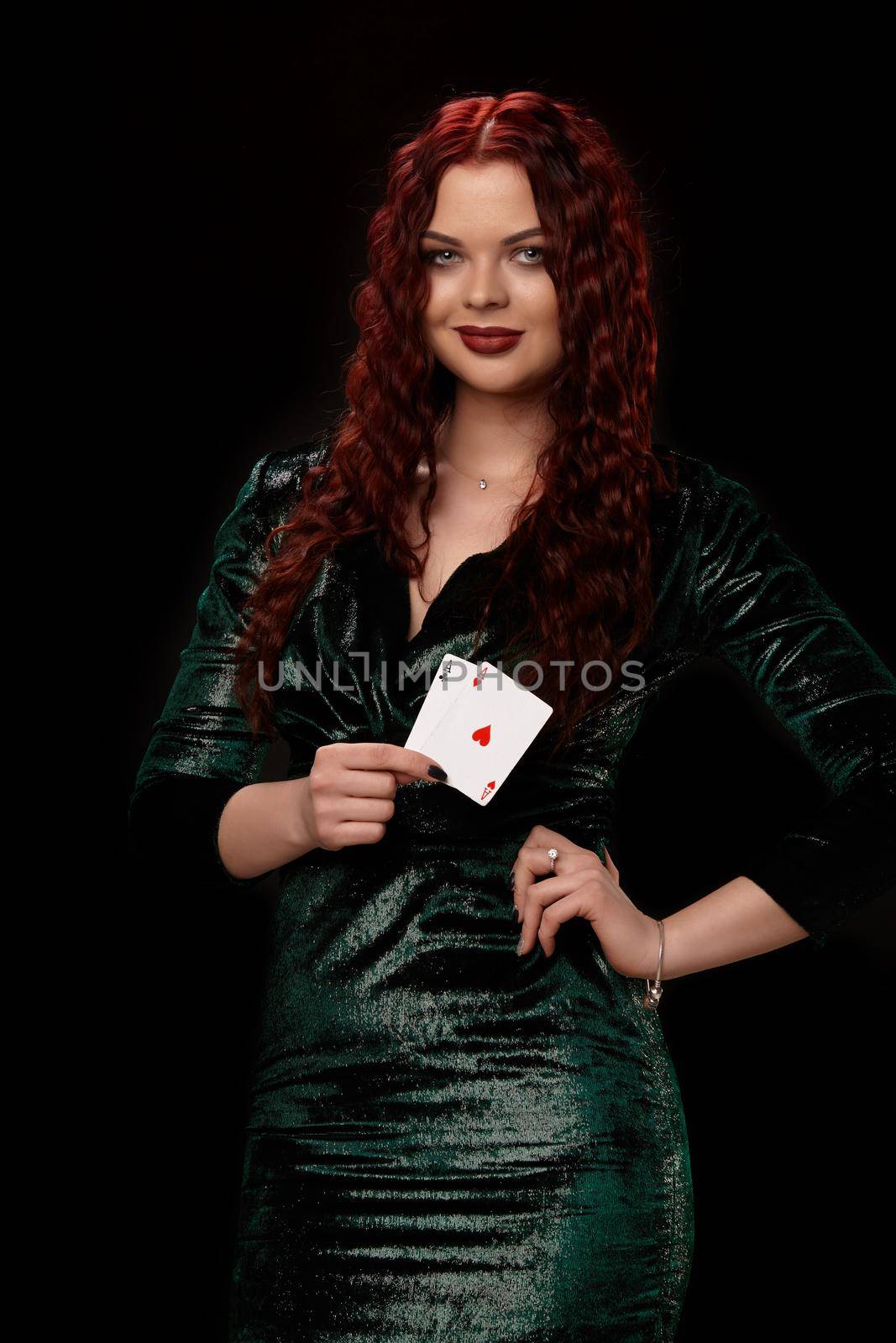 Redheaded woman whith a curly hair posing with a playing cards in her hands, on black background Win casino poker slots
