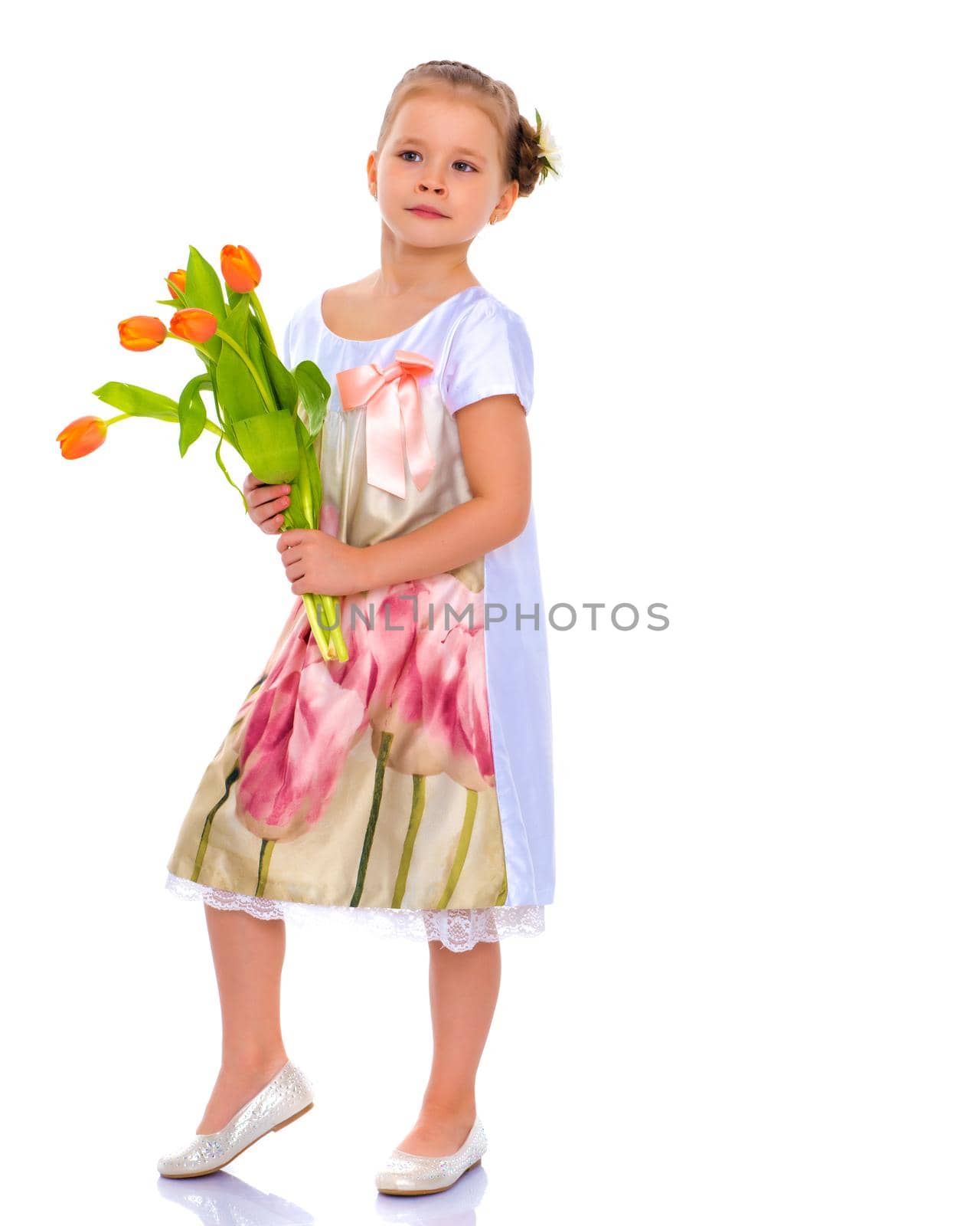 A cute little girl with a bouquet of tulips, in the spring in the studio. The concept of the awakening of nature after winter, the expectation of summer.