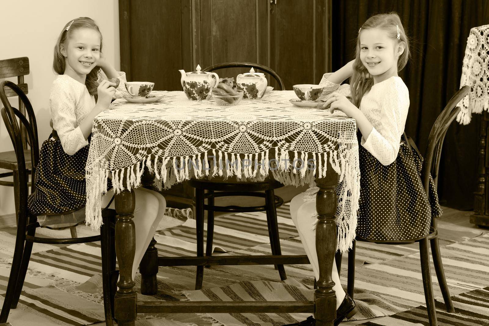 Girls Twins drinking tea at an antique table with a lace tablecl by kolesnikov_studio