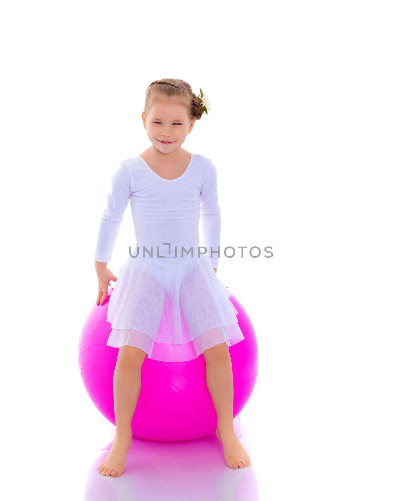 A charming little girl is engaged in fitness with a ball. The concept of gymnastics, health and sports. Isolated on white background.