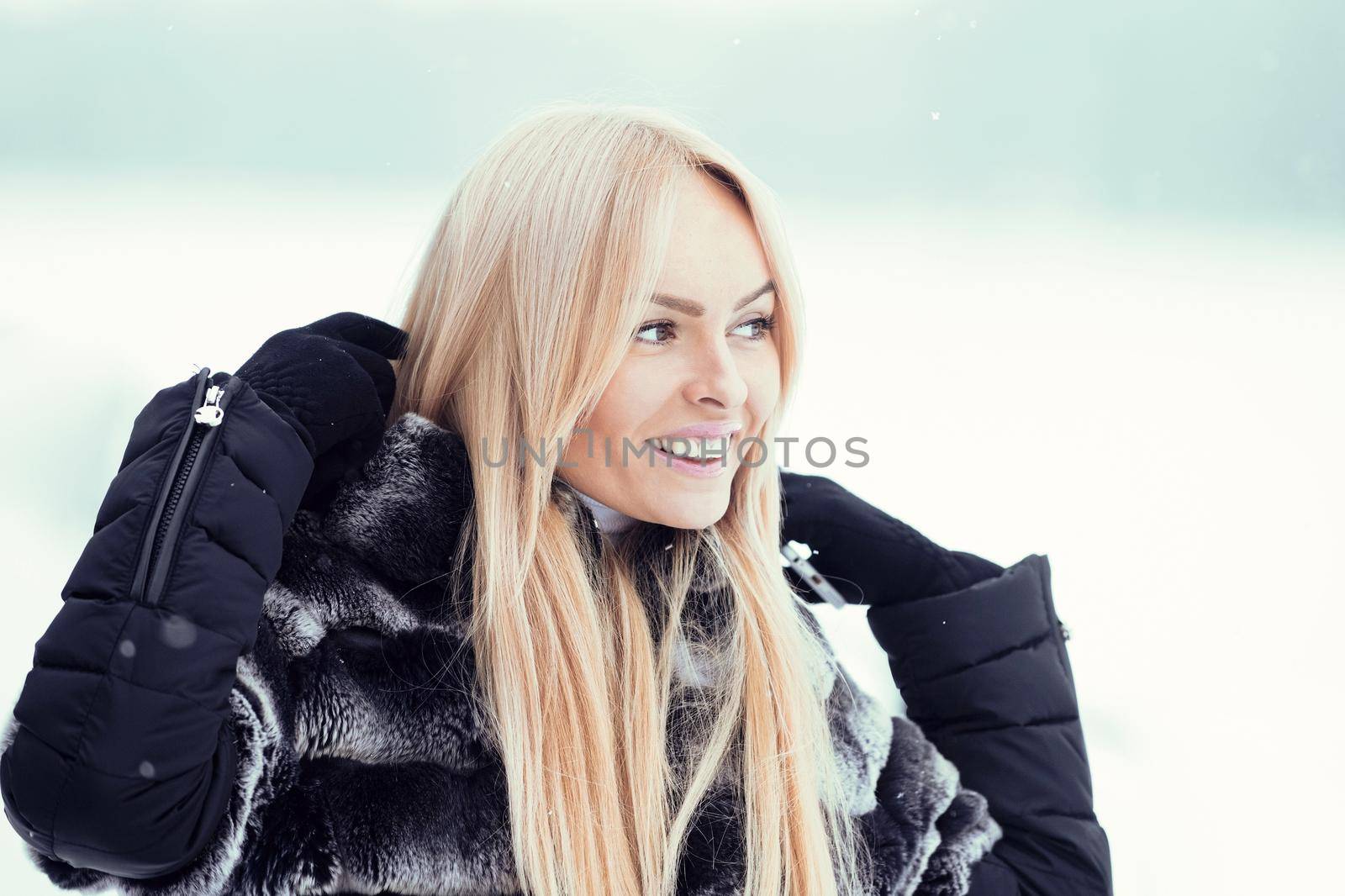 Happy woman smiling on white snow landscape. Girl with long blond hair on winter day. Model in fur jacket on snowy nature. Christmas and new year.