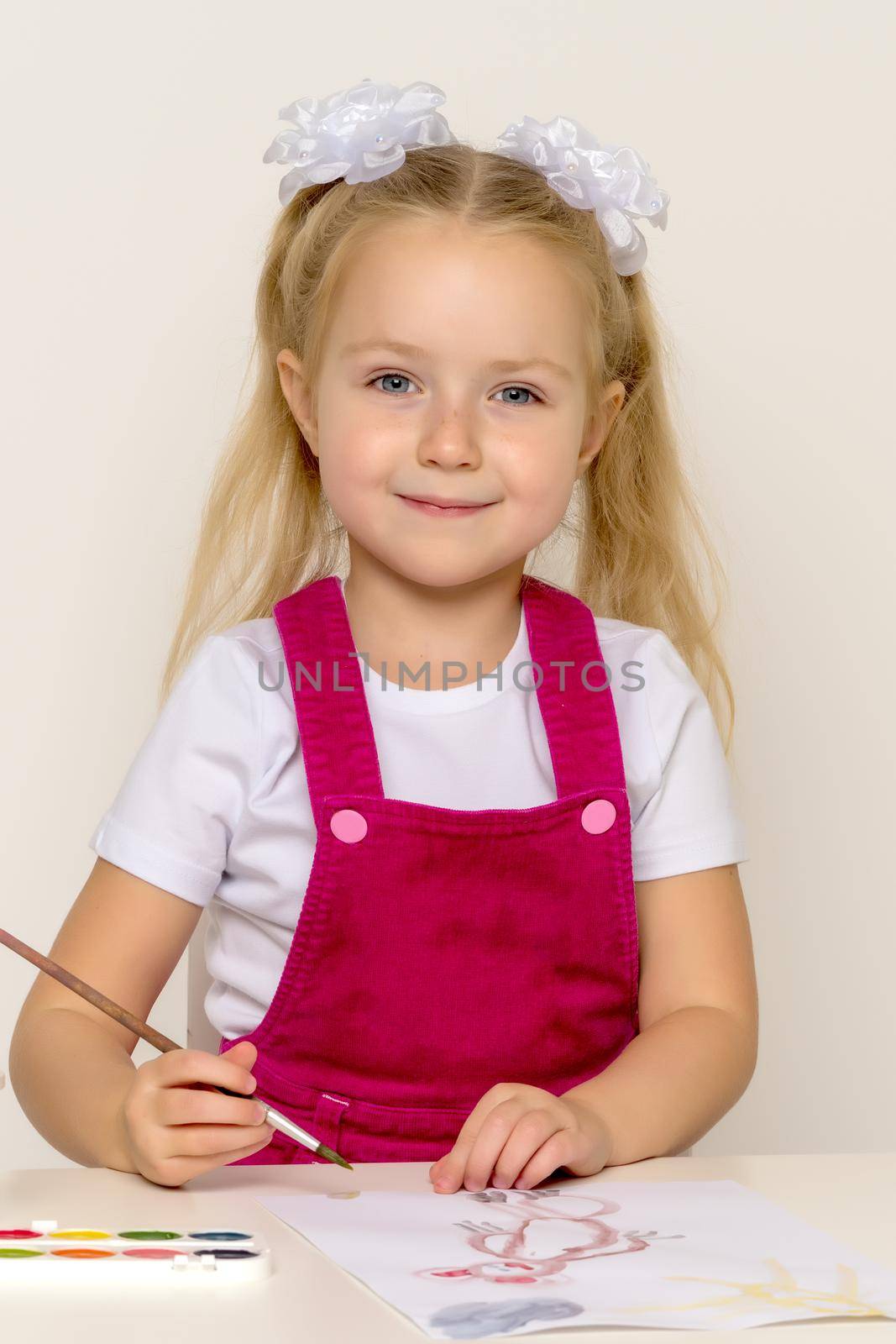 Little girl draws paints on a sheet of paper. Concept kindergarten, montessori education.