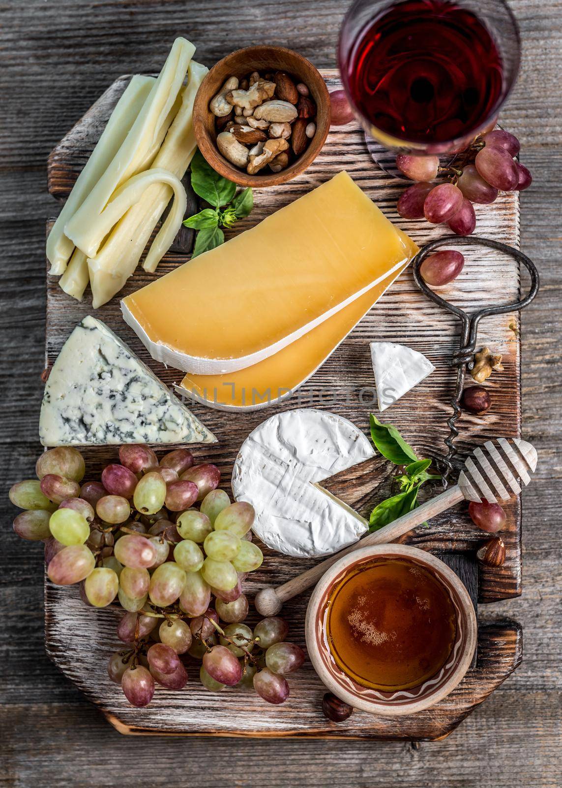 Cheese plate served with wine, nuts and honey top view