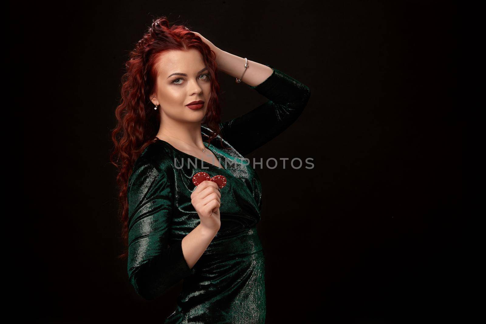 Sexy redheaded woman whith a curly hair posing with chips in her hands and smiling, on black background Win casino holdem poker slots