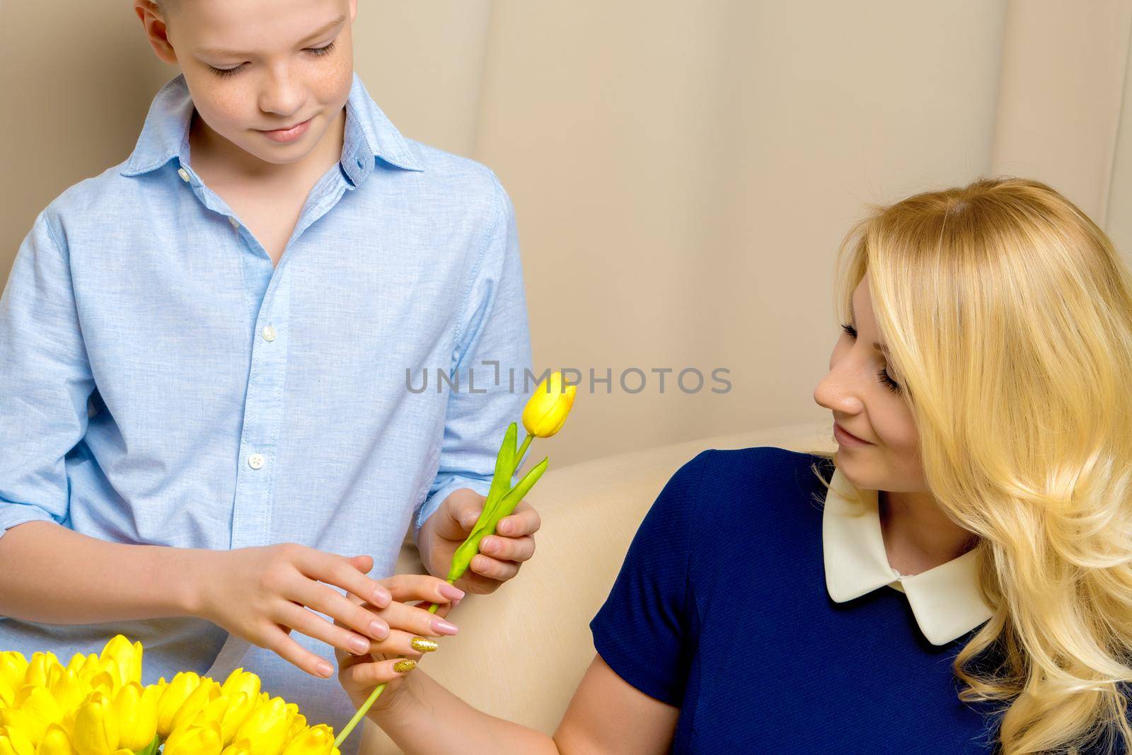Happy young mother and her son near a bouquet of tulips. by kolesnikov_studio