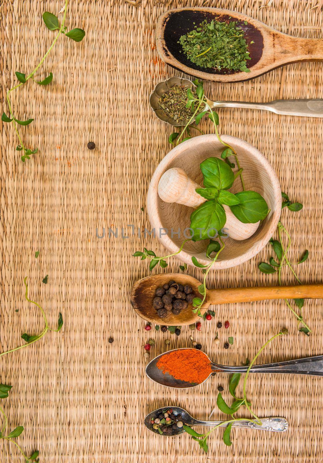 mortar with herbs and spices on a straw mat background