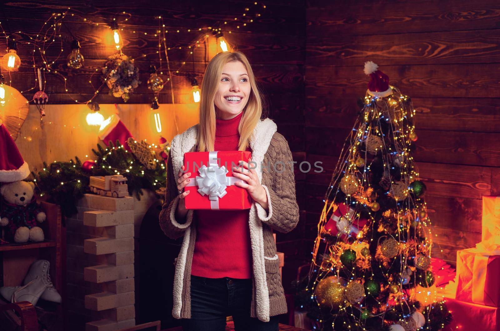 Beauty Santa girl. Happy woman with gift by the fireplace near the Christmas tree