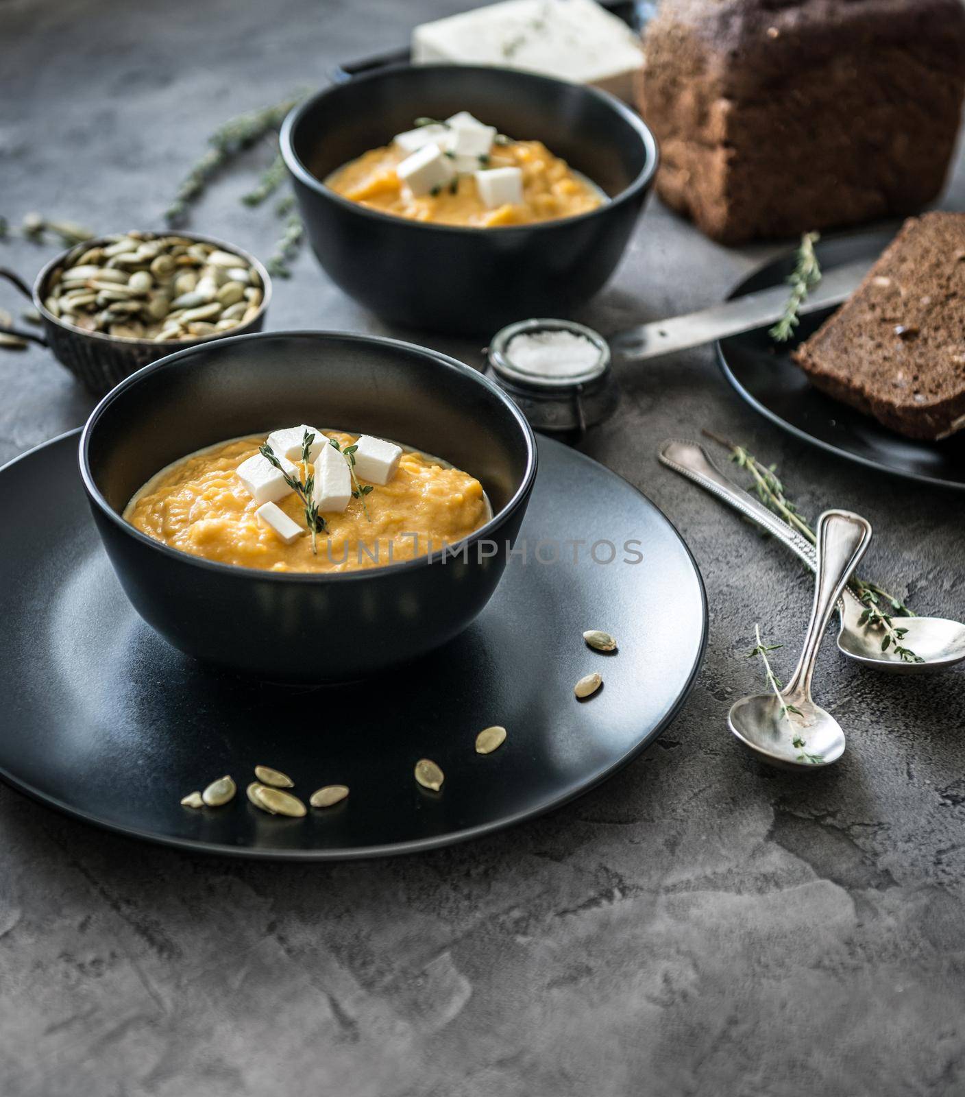 pumpkin soup in black plates on a gray concrete background