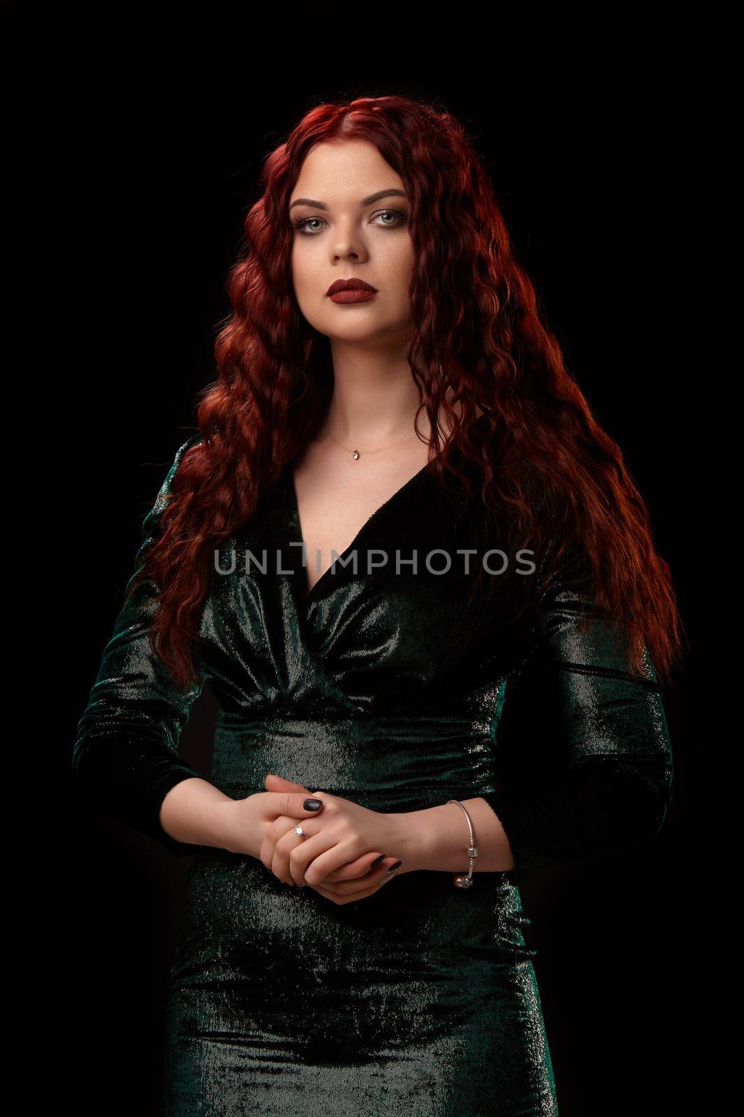 Young beautiful redhead woman with curly hair poses for the camera over black. Win casino poker slots