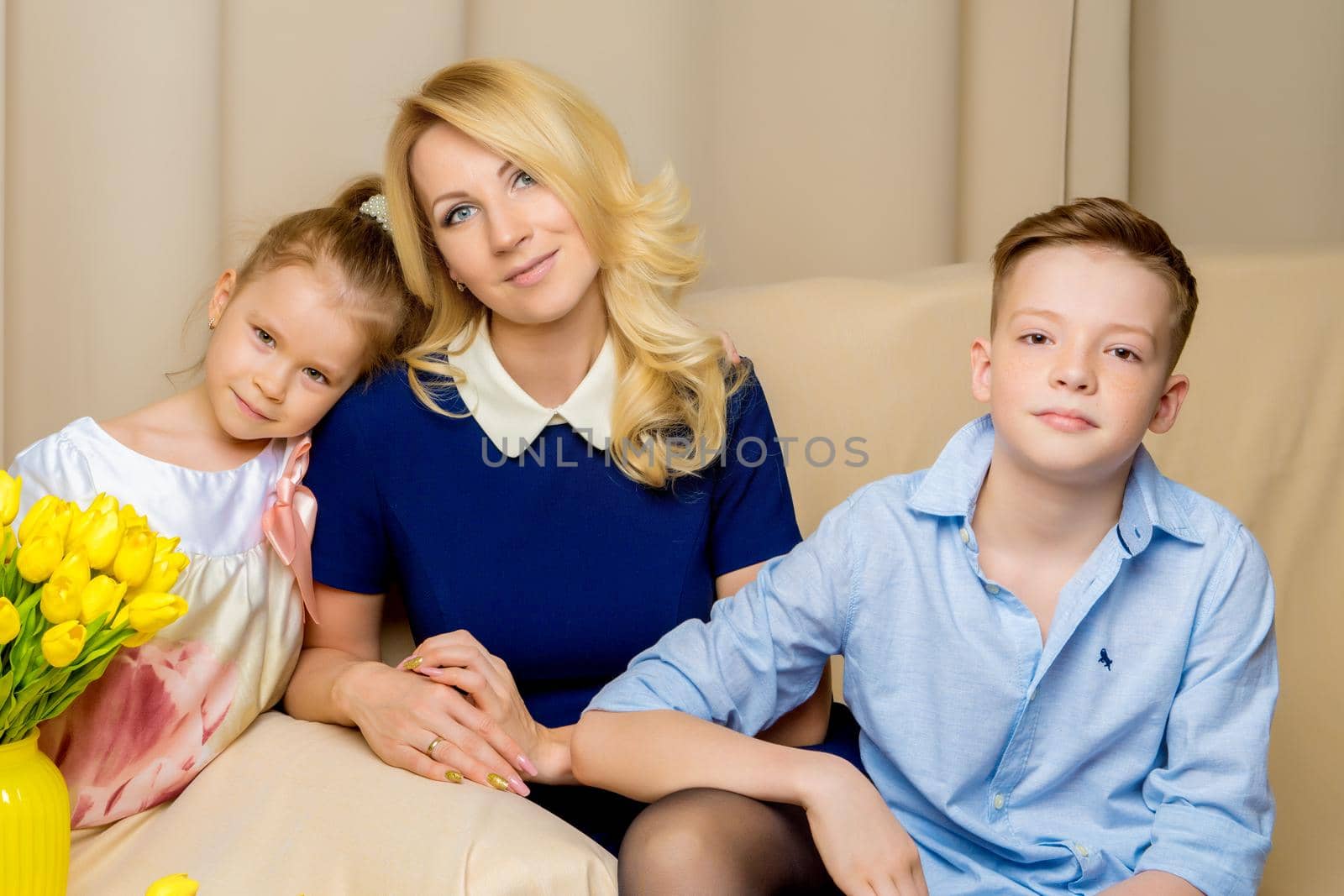Beautiful young mother with her son and daughter in the studio on the couch. The concept of family values, holidays.