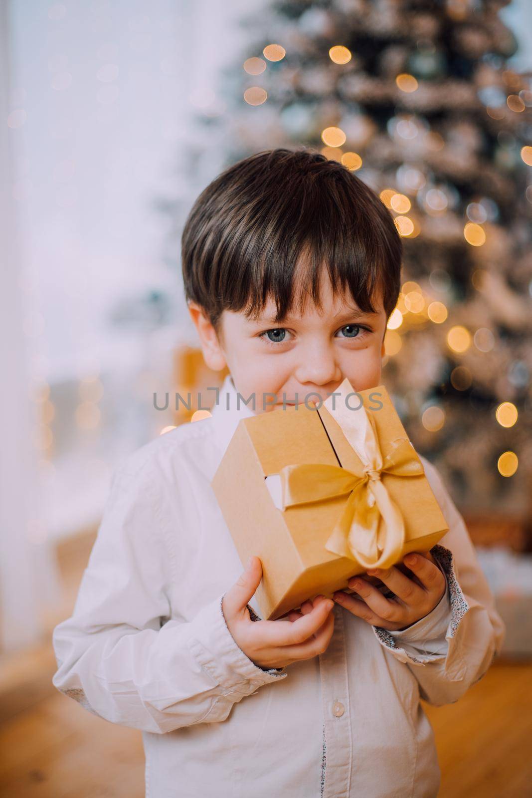 A boy with a New Year's gift under the tree lifestyle. New Year and Christmas. Festive decoration. New Year's gift