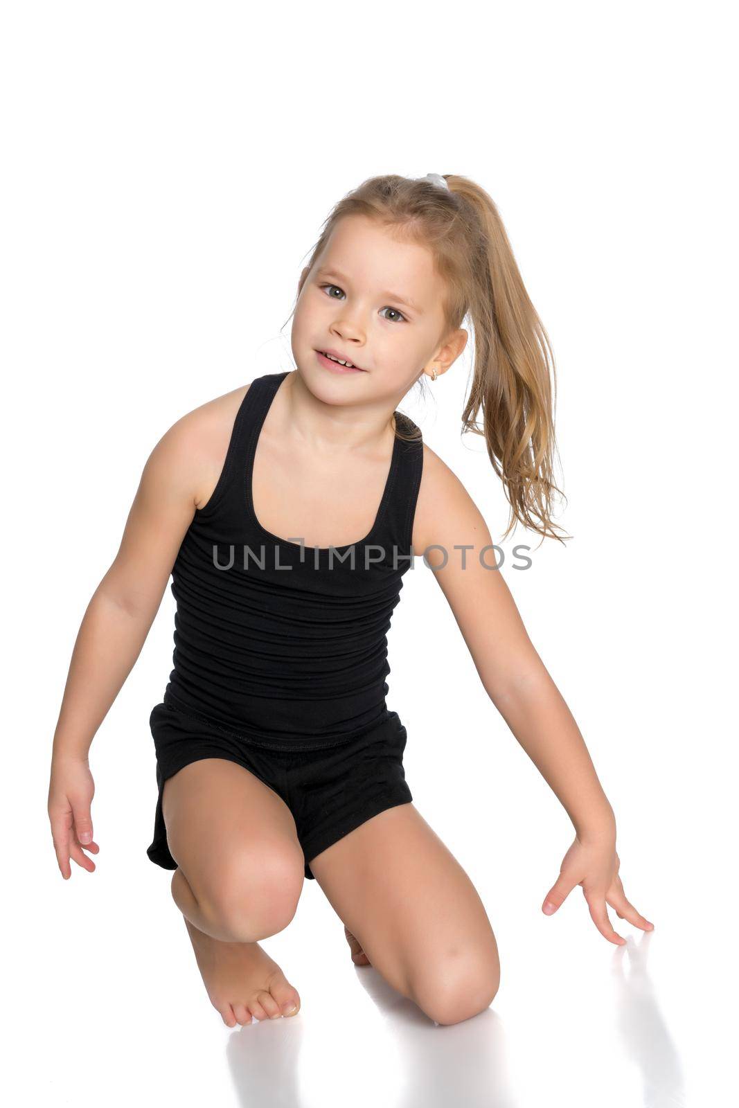 A girl gymnast performs an acrobatic element on the floor. The concept of childhood, sport, healthy lifestyle. Isolated on white background.