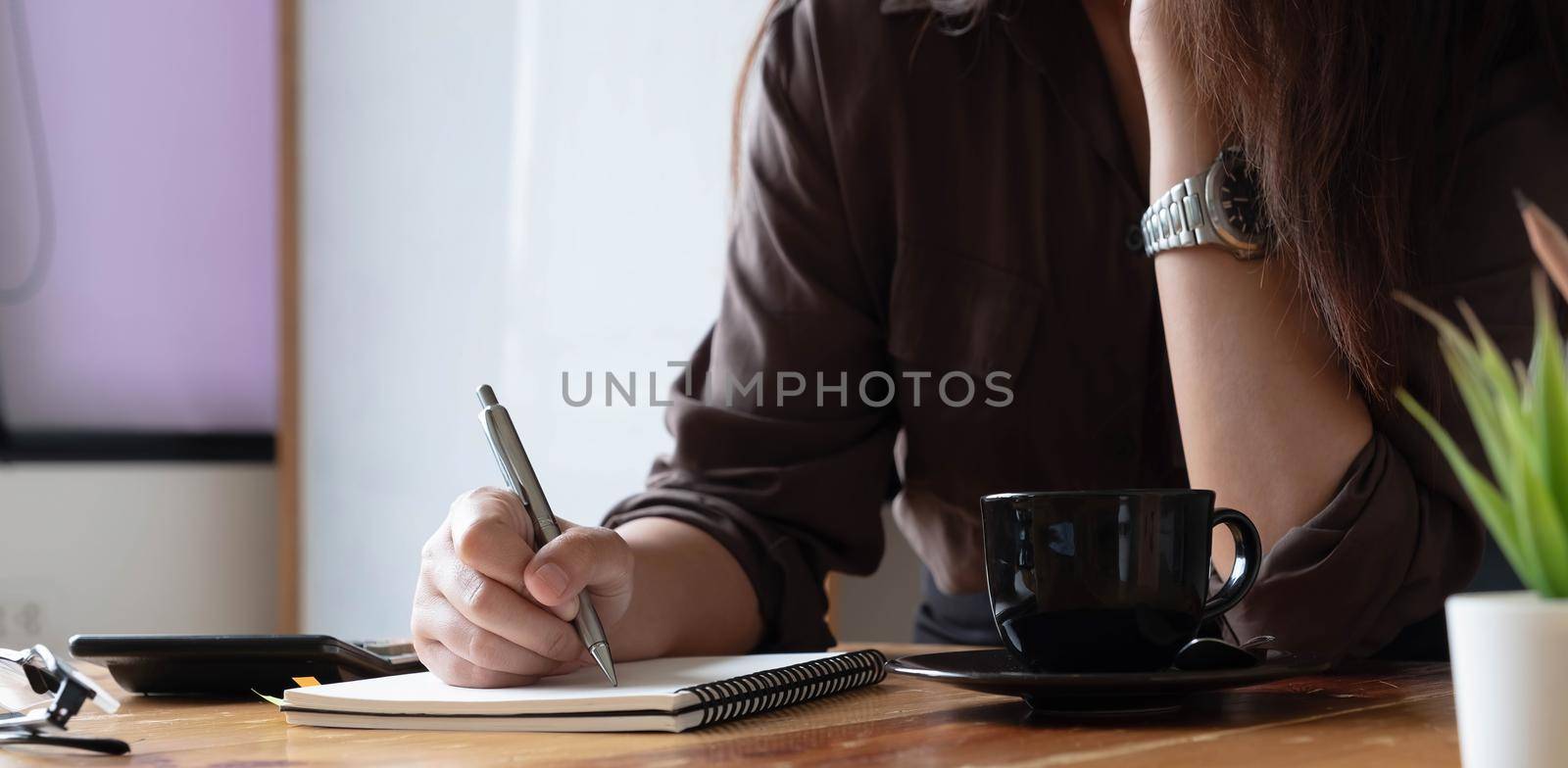 Cropped photo hand of woman writing making list taking notes in notepad working or learning online by wichayada